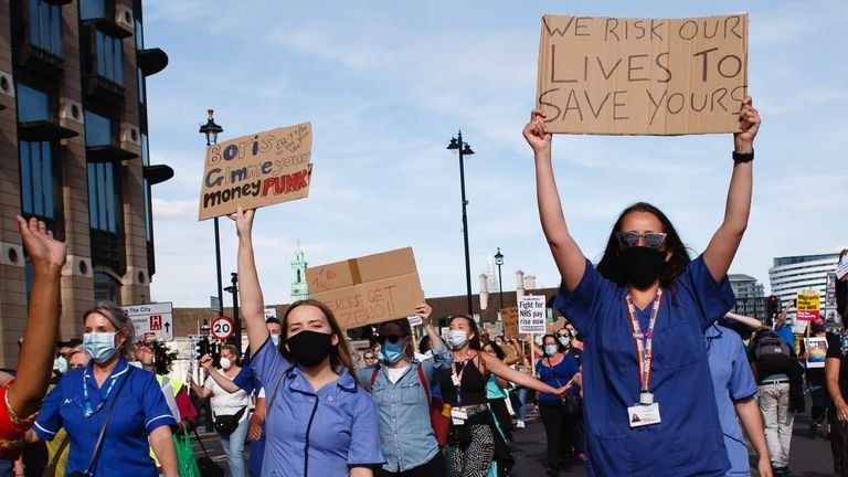 National Health Service (NHS) staff wearing masks are seen protesting their exclusion from a recently announced public sector pay hike in Parliament Square.  Around 900,000 public sector workers across the UK are expected to receive an above-inflation pay rise this year as a thank you from the Treasury for their efforts during the coronavirus pandemic.  The salary increase is exclusive to nurses and other frontline staff, however, due to a three-year salary deal they negotiated in 2018 that led to them being m
