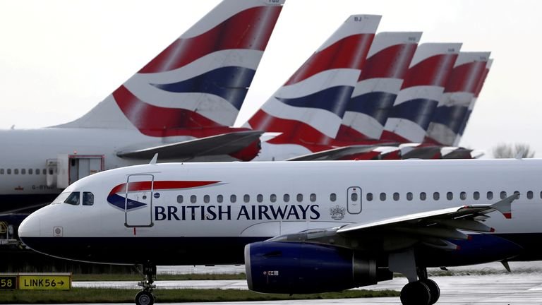FILE PHOTO: A British Airways plane walks past the tail fins of an aircraft parked near Terminal 5 at Heathrow Airport in London, Britain March 14, 2020