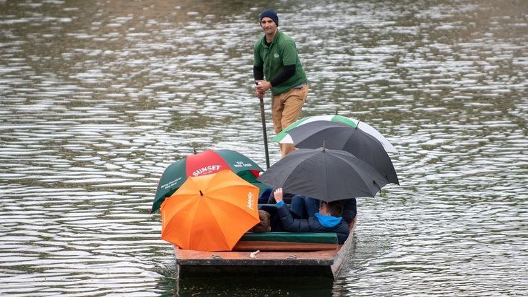 People shelter from the rain while trying to row a boat in Cambridge