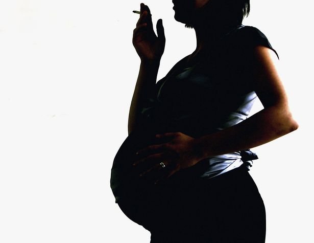 A pregnant woman is seen holding a cigarette