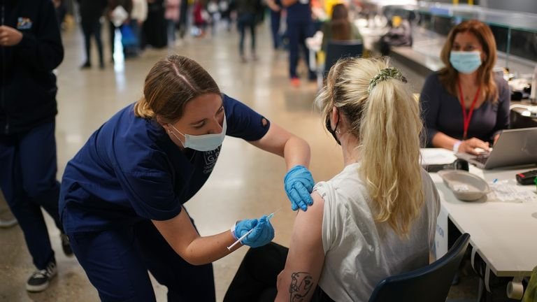 Rosi Stamp, 25, receives a Pfizer BioNTech COVID-19 vaccine at an NHS vaccination clinic at Tottenham Hotspur Stadium in north London.